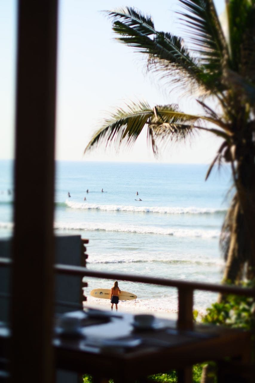 A surfer crossing the beach at low tide