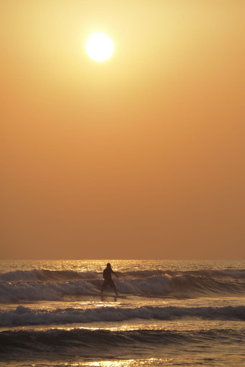 A lone surfer riding a wave at golden hour
