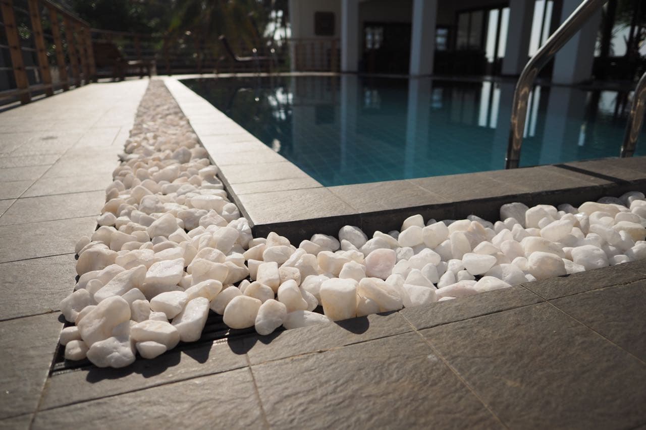 The pool edge with white pebbles and the ocean beyond